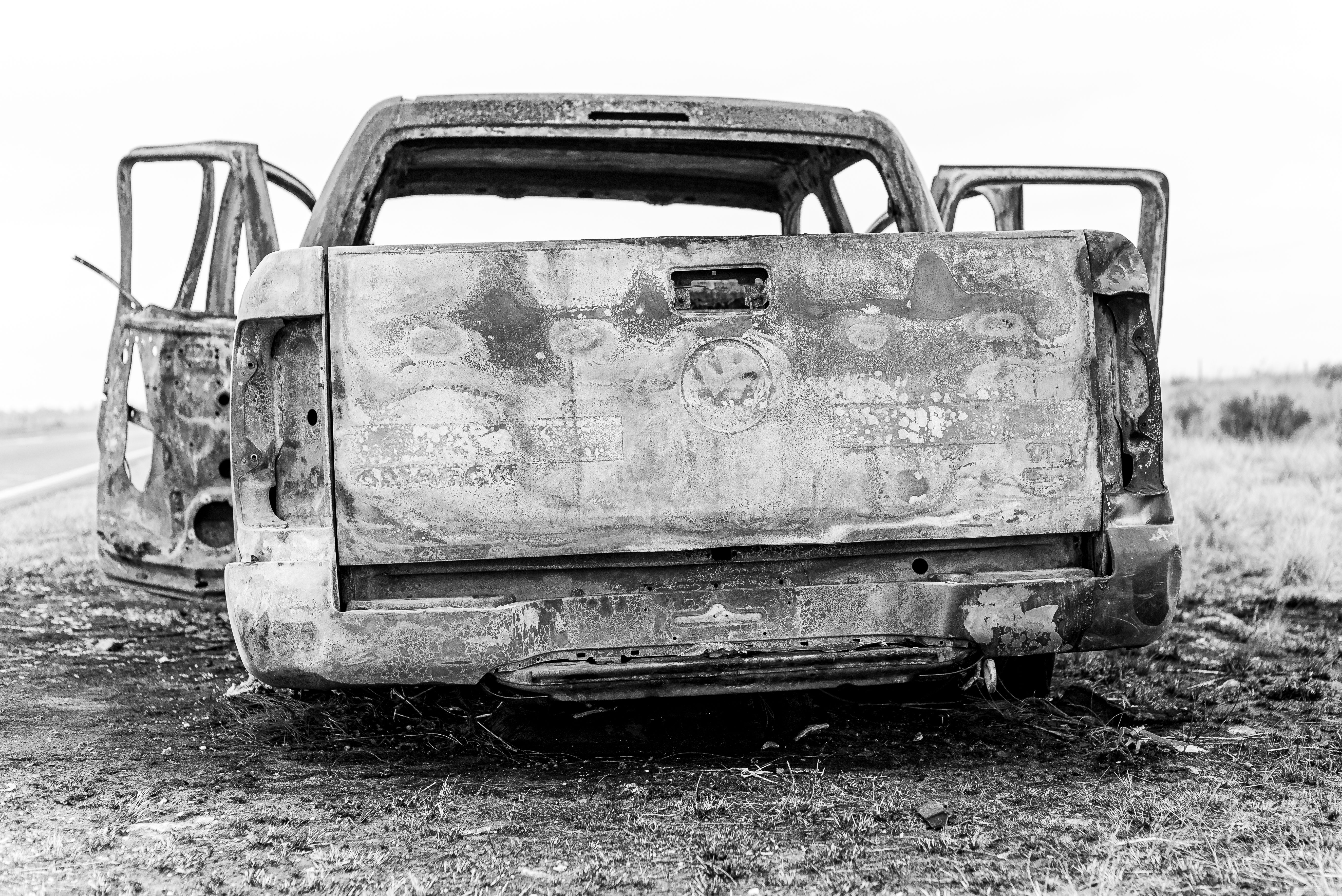 Burned pickup truck at a rural roadside crash scene.