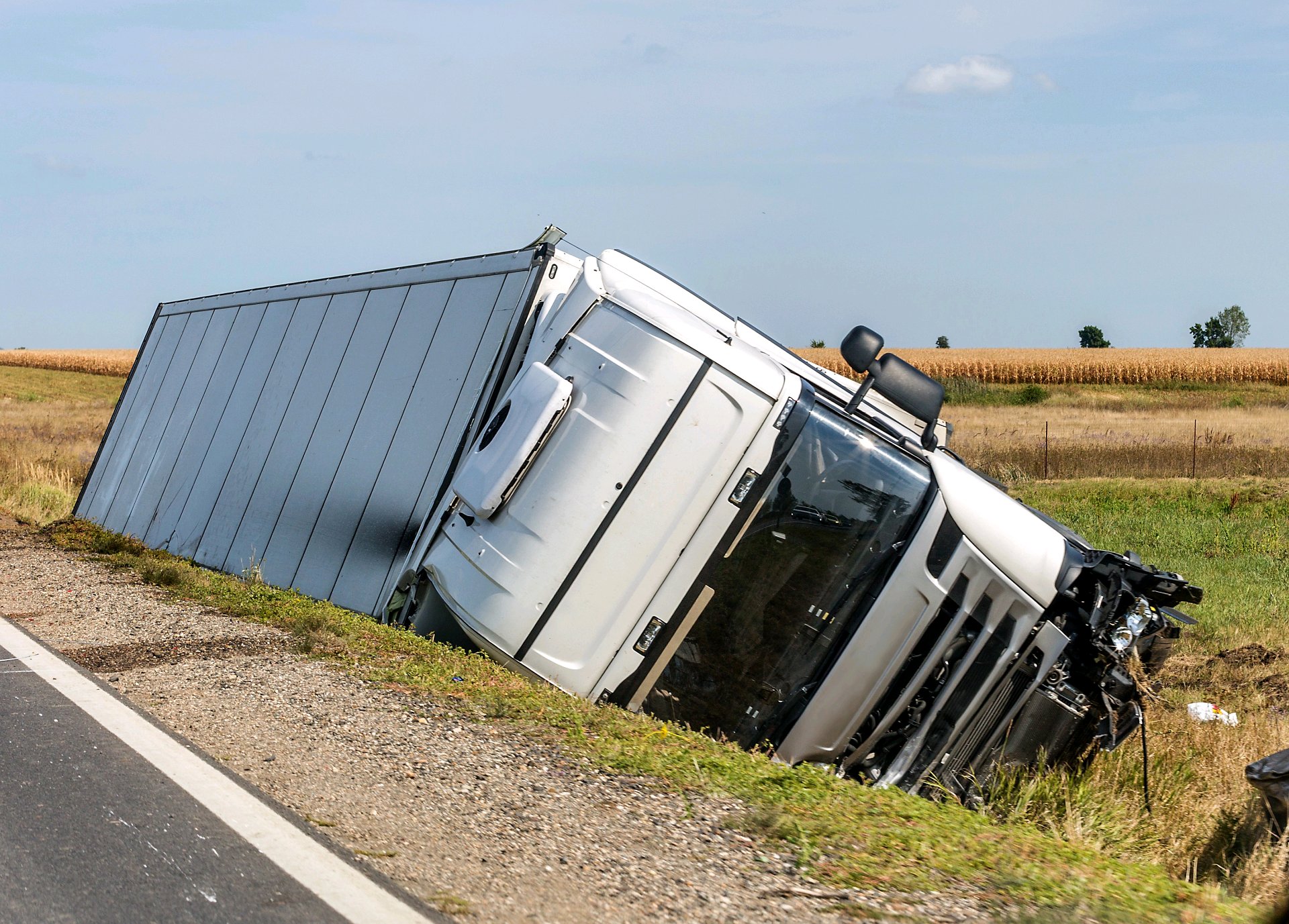 A tractor-trailer on its side beside a highway after a rollover crash.